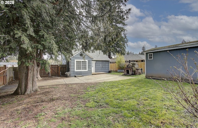 view of yard featuring an outdoor structure, a fenced backyard, and a patio area