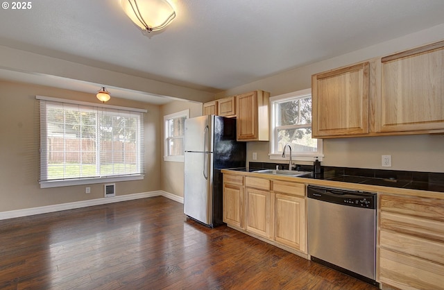 kitchen featuring dark wood-style floors, light brown cabinets, visible vents, a sink, and stainless steel appliances