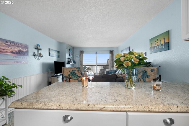 1415 NW 31st Pl Unit 166, Lincoln City, OR 97367 - kitchen featuring white appliances, a textured ceiling, white cabinets, tasteful backsplash, and a wainscoted wall