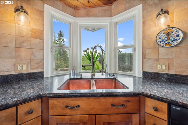 kitchen featuring dark stone countertops, dishwasher, sink, and wood ceiling