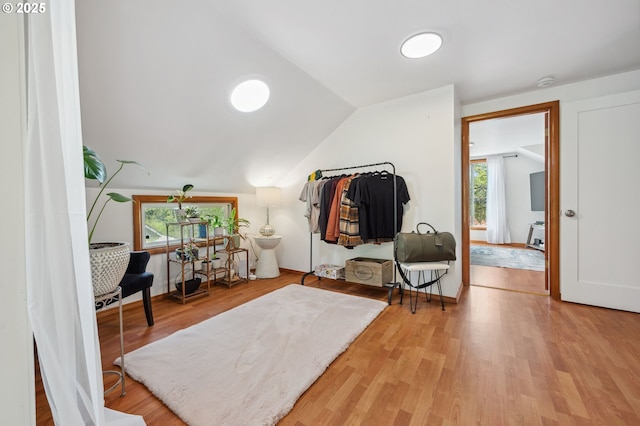 living area featuring hardwood / wood-style flooring, vaulted ceiling, and plenty of natural light