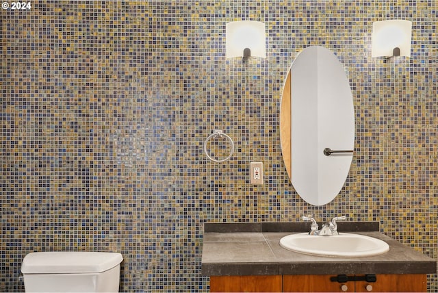 bathroom with tile walls, vanity, and toilet