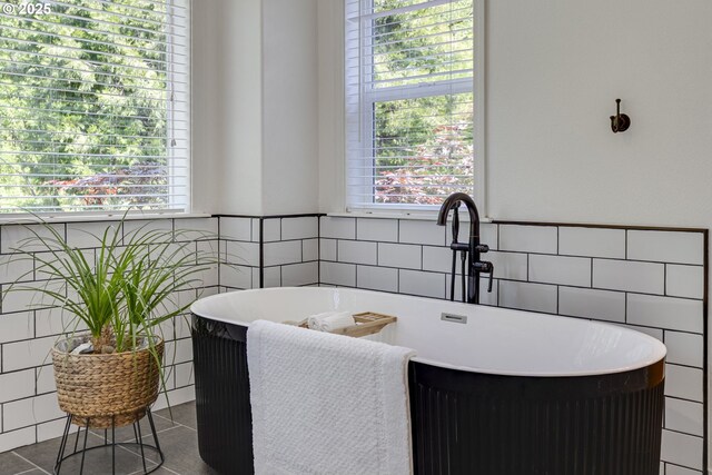 3011 Sabo Ln, West Linn, OR 97068 - bathroom featuring tile walls, a freestanding tub, plenty of natural light, tile patterned flooring, and a wainscoted wall