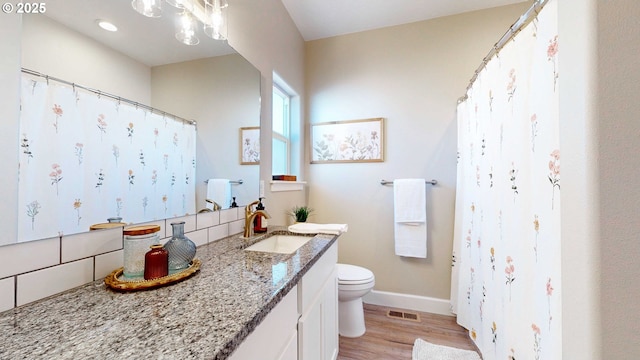 bathroom featuring toilet, wood finished floors, visible vents, vanity, and baseboards