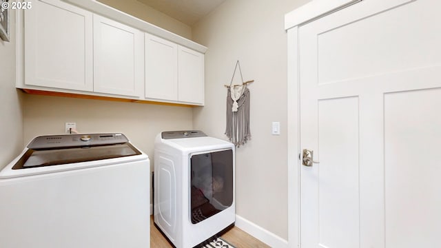 laundry area featuring light wood-style floors, washer and clothes dryer, cabinet space, and baseboards