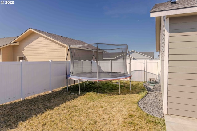 view of yard with a trampoline and a fenced backyard