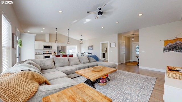 living room with vaulted ceiling, recessed lighting, light wood-type flooring, and baseboards