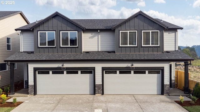 view of front of property with a garage, roof with shingles, board and batten siding, and stone siding