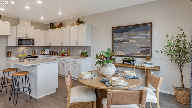 kitchen with dark wood-style floors, tasteful backsplash, stainless steel microwave, and white cabinetry