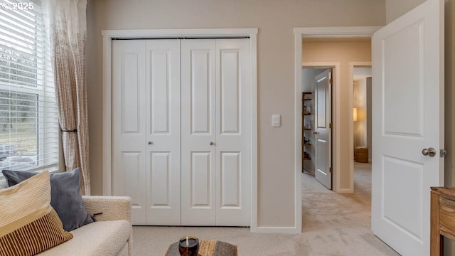 living area featuring light carpet and baseboards