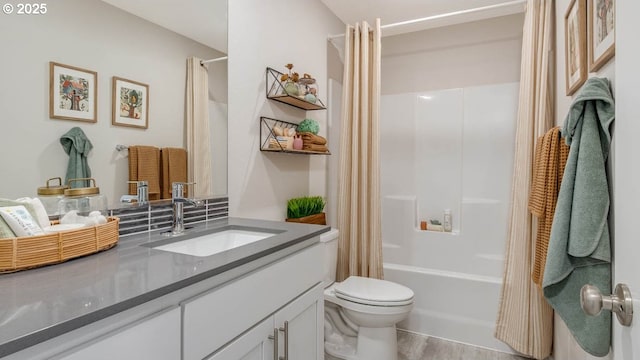 bathroom featuring toilet, shower / bath combo with shower curtain, wood finished floors, and vanity