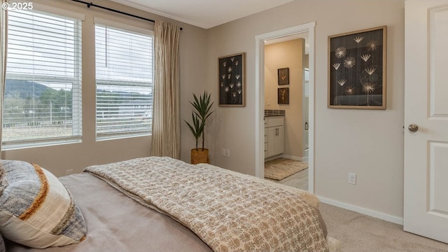 bedroom featuring ensuite bath, baseboards, and light colored carpet