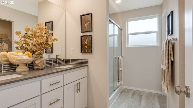 bathroom with baseboards, a shower stall, vanity, and wood finished floors