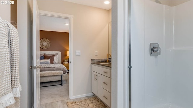 full bathroom featuring a stall shower, ensuite bath, vanity, and baseboards