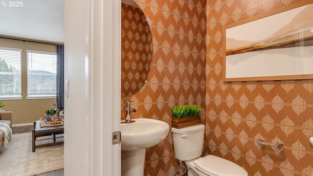 bathroom featuring a sink, tile walls, and toilet