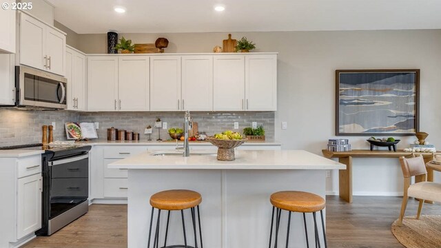 kitchen with stainless steel appliances, a sink, and white cabinetry