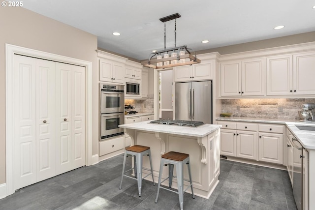 kitchen featuring a breakfast bar area, a kitchen island, white cabinetry, appliances with stainless steel finishes, and decorative backsplash