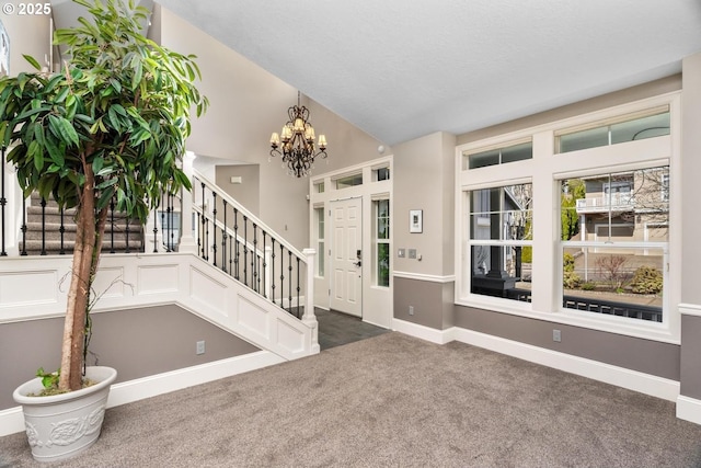 carpeted foyer featuring a textured ceiling, lofted ceiling, a notable chandelier, baseboards, and stairway