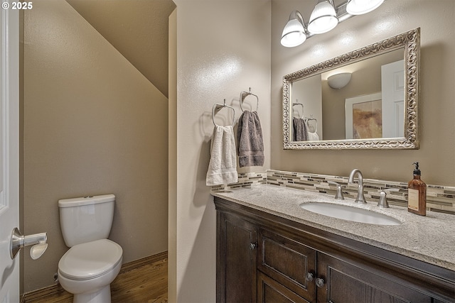 bathroom featuring vanity, decorative backsplash, toilet, and wood finished floors