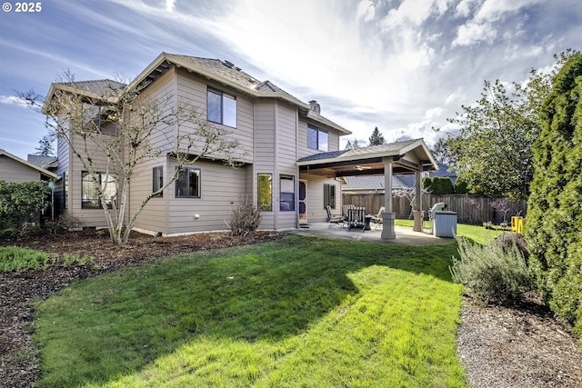 rear view of house featuring a patio, fence, a yard, and a chimney
