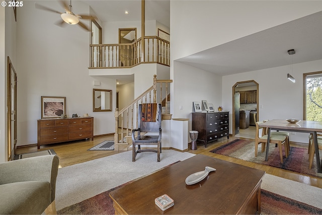 living area featuring stairs, a high ceiling, wood finished floors, and arched walkways