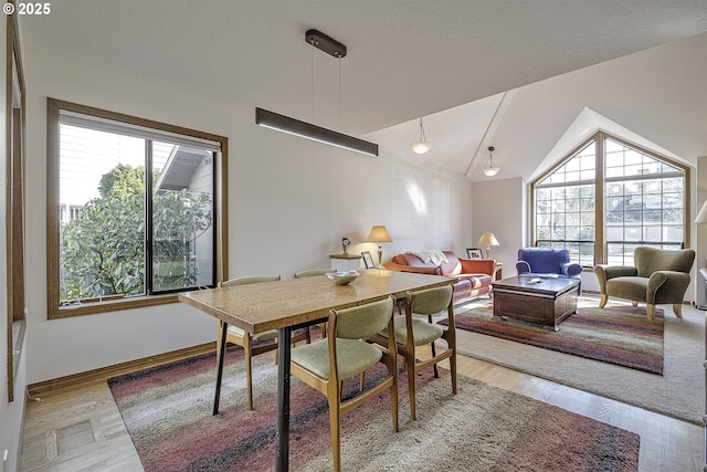 dining space with a wealth of natural light, visible vents, wood finished floors, and vaulted ceiling