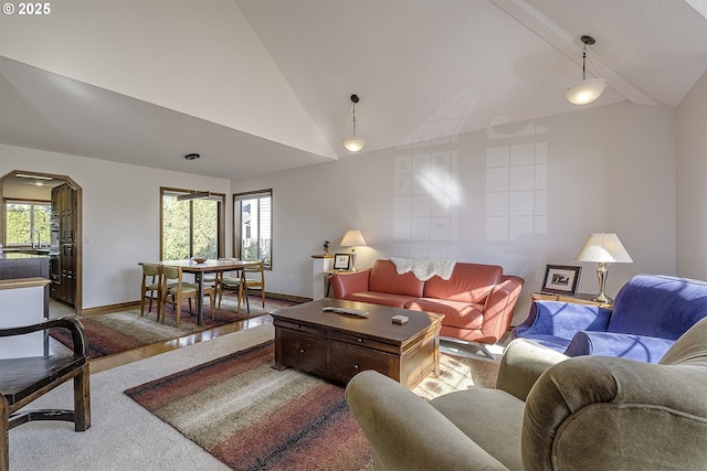 carpeted living area with arched walkways, baseboards, and high vaulted ceiling
