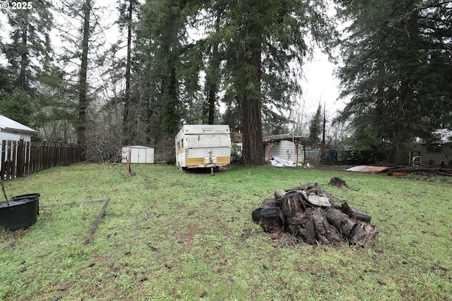 view of yard with a storage shed, fence, and an outbuilding