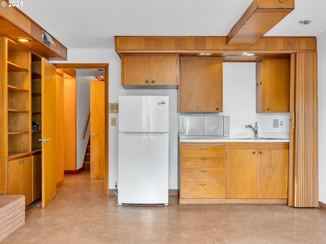 4915 Leif Erikson Dr, Astoria, OR 97103 - kitchen featuring freestanding refrigerator, light countertops, a sink, light flooring, and brown cabinets