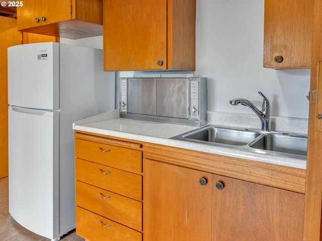 4915 Leif Erikson Dr, Astoria, OR 97103 - kitchen with freestanding refrigerator, a sink, light countertops, and brown cabinets