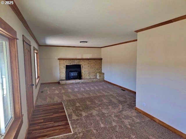 967 NW 2nd St, Prineville, OR 97754 - unfurnished living room featuring ornamental molding, carpet, healthy amount of natural light, and a brick fireplace