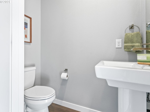 bathroom with toilet, baseboards, and wood finished floors