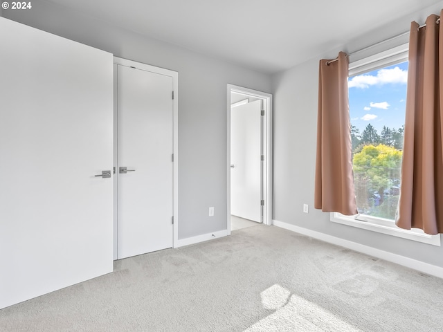 unfurnished bedroom featuring light carpet and baseboards