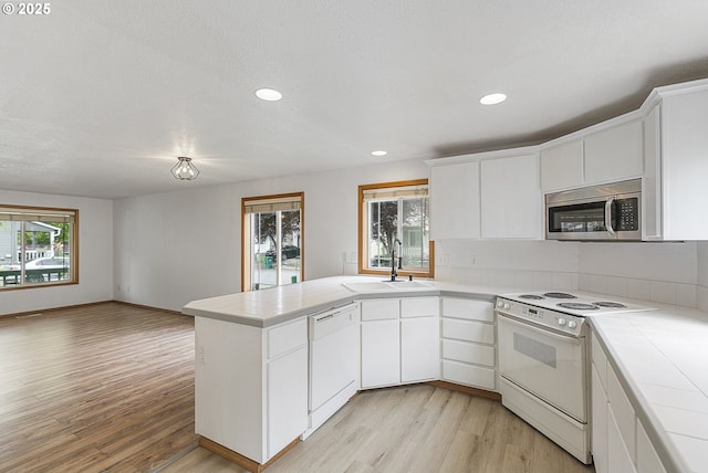 18450 SW Longacre St, Beaverton, OR 97003 - kitchen featuring white appliances, a sink, a peninsula, light wood-type flooring, and recessed lighting