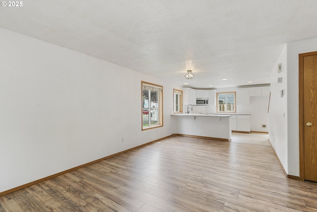 18450 SW Longacre St, Beaverton, OR 97003 - unfurnished living room with light wood finished floors, a sink, baseboards, and recessed lighting