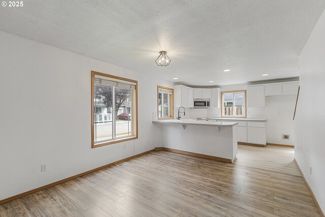 18450 SW Longacre St, Beaverton, OR 97003 - unfurnished living room featuring light wood-style flooring, baseboards, a sink, and recessed lighting