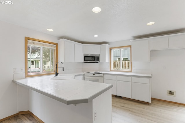 18450 SW Longacre St, Beaverton, OR 97003 - kitchen with stainless steel microwave, electric range, a sink, light wood-style floors, and a peninsula
