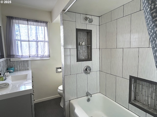 full bathroom featuring vanity, tiled shower / bath, and toilet