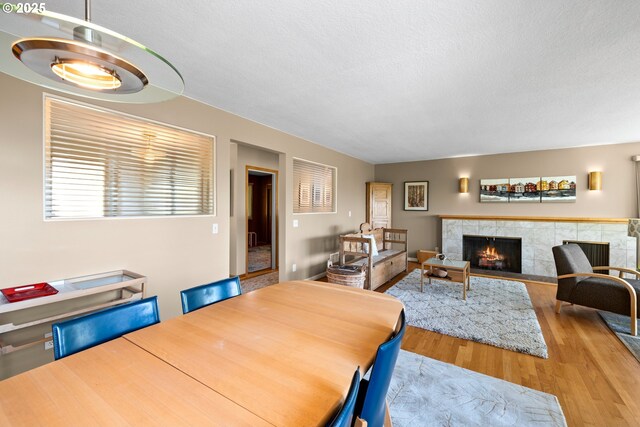 dining area with wood finished floors, a tile fireplace, and a textured ceiling
