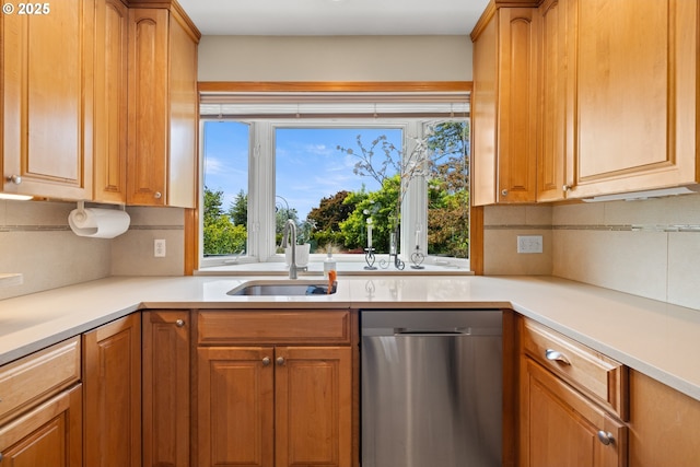 kitchen with dishwasher, a sink, decorative backsplash, light countertops, and brown cabinets