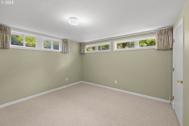 basement with light carpet, a textured ceiling, and baseboards