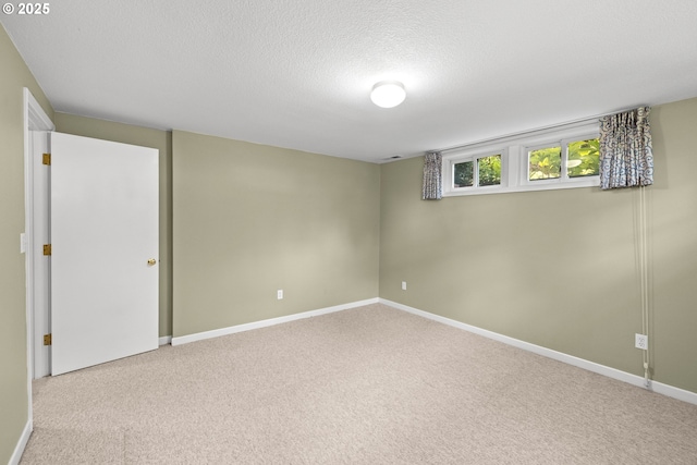 basement featuring carpet, a textured ceiling, and baseboards