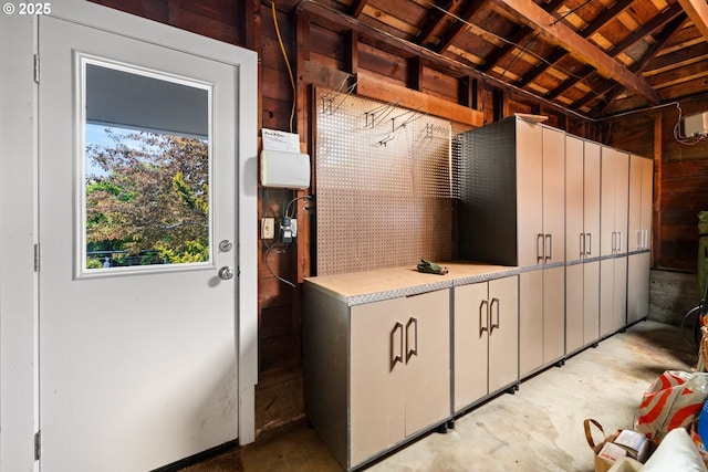 mudroom with unfinished concrete floors, wood ceiling, and wood walls