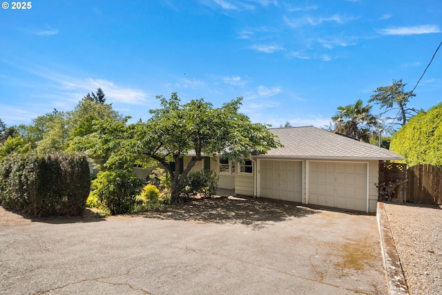 view of front of home with asphalt driveway, an attached garage, and fence