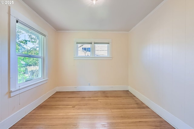spare room with crown molding, light wood finished floors, and baseboards