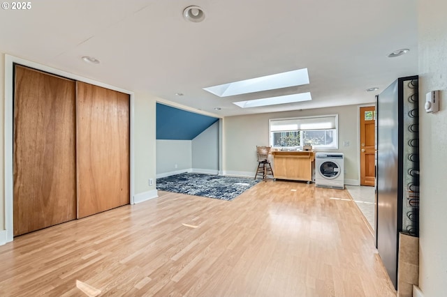 bonus room with recessed lighting, washer / dryer, lofted ceiling with skylight, baseboards, and light wood-style flooring