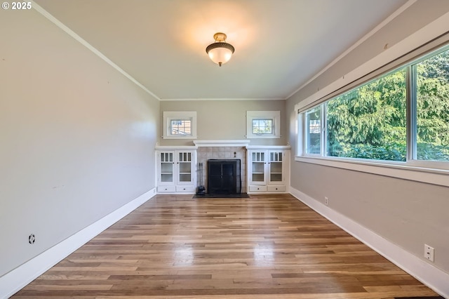 unfurnished living room with a wealth of natural light, ornamental molding, and a tile fireplace