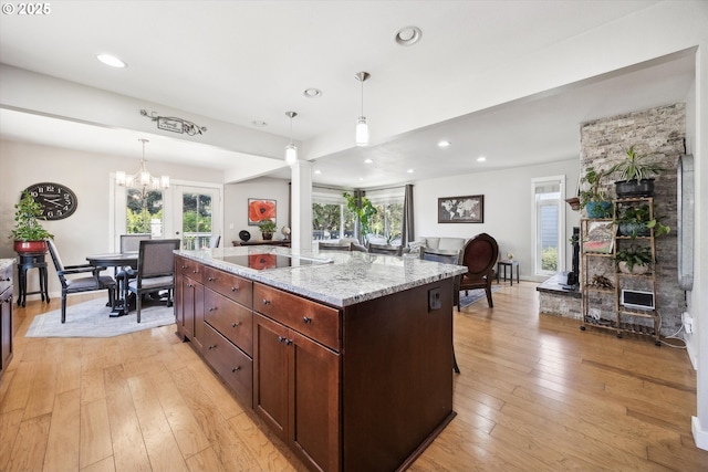 kitchen featuring decorative columns, light stone countertops, light wood-type flooring, black electric stovetop, and recessed lighting