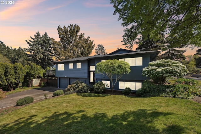 bi-level home with concrete driveway, a front lawn, and a garage