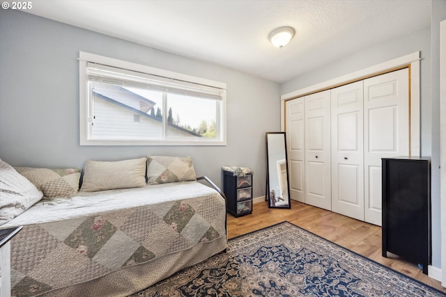 bedroom with baseboards, wood finished floors, and a closet